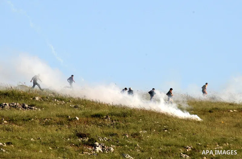 Palestinian youths run in tear gas as they clash with Israeli soldiers during a demonstrate against Jewish settlements in the northern West Bank village of Iraq Burin on May 7, 2011. Photo by Wagdi Eshtayah