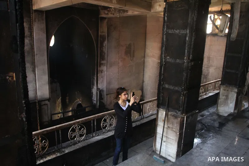 An Egyptians Christian woman takes photos at the damaged Virgin Mary church in the popular area of Imbaba in the Egyptian capital of Cairo on May 8, 2011, after overnight clashes between Muslims and Christians which left...