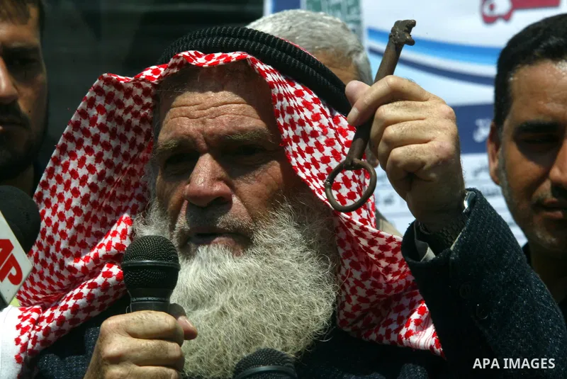Palestinian man holds up a key allegedly from his house as Palestinians gather around a giant key symbolising the keys to houses left by Palestinians in 1948 in the preparation to mark the 62nd anniversary of the "Nakba"...