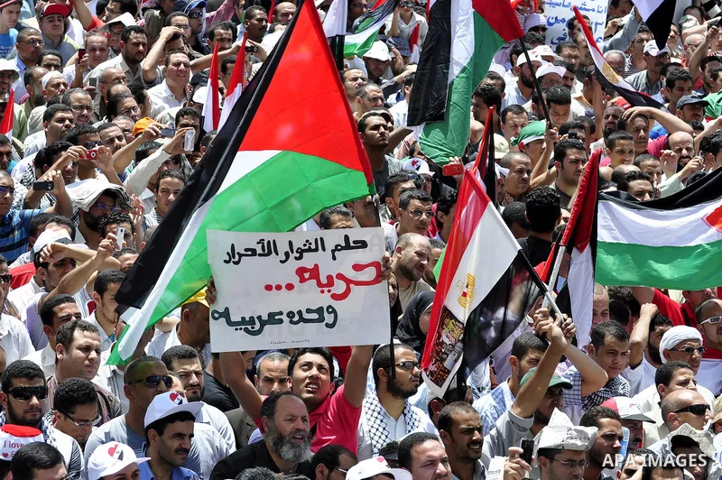 Egyptian demonstrators wave Palestinian flags and Egyptian flags during a rally at Cairo's Tahrir Square on May 13, 2011 during a protest calling for national unity after attacks on Egyptian churches, and solidarity with...