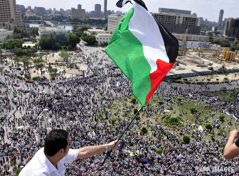 Egyptian demonstrators wave Palestinian flags and Egyptian flags during a rally at Cairo's Tahrir Square on May 13, 2011 during a protest calling for national unity after attacks on Egyptian churches, and solidarity with...