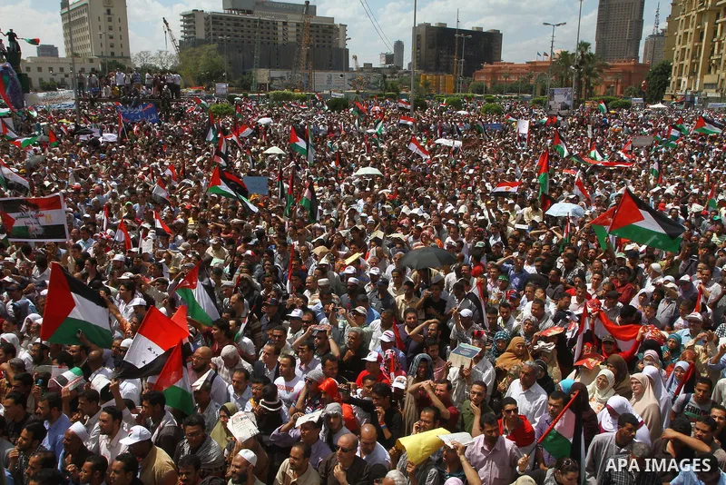 Egyptian demonstrators wave Palestinian flags and Egyptian flags during a rally at Cairo's Tahrir Square on May 13, 2011 during a protest calling for national unity after attacks on Egyptian churches, and solidarity with...