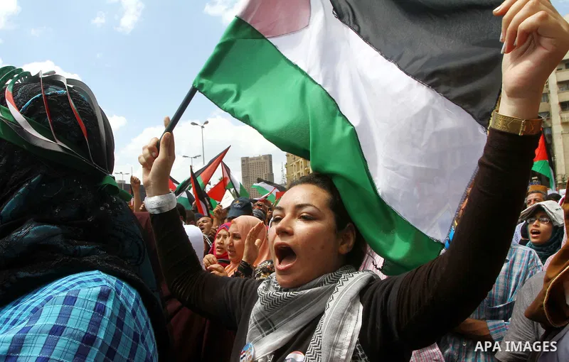 Egyptian demonstrators wave Palestinian flags and Egyptian flags during a rally at Cairo's Tahrir Square on May 13, 2011 during a protest calling for national unity after attacks on Egyptian churches, and solidarity with...