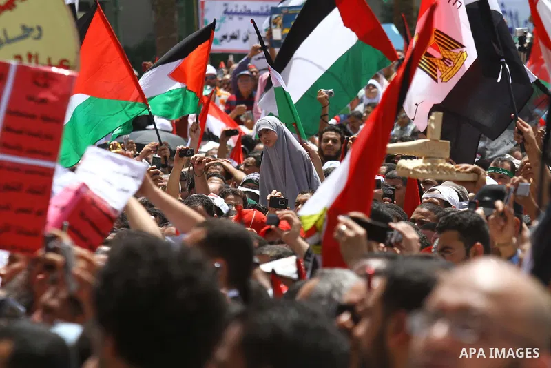 Egyptian demonstrators wave Palestinian flags and Egyptian flags during a rally at Cairo's Tahrir Square on May 13, 2011 during a protest calling for national unity after attacks on Egyptian churches, and solidarity with...