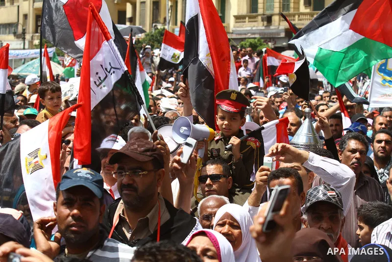 Egyptian demonstrators wave Palestinian flags and Egyptian flags during a rally at Cairo's Tahrir Square on May 13, 2011 during a protest calling for national unity after attacks on Egyptian churches, and solidarity with...