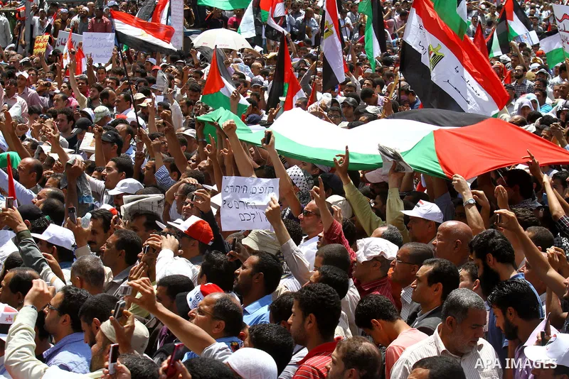 Egyptian demonstrators wave Palestinian flags and Egyptian flags during a rally at Cairo's Tahrir Square on May 13, 2011 during a protest calling for national unity after attacks on Egyptian churches, and solidarity with...