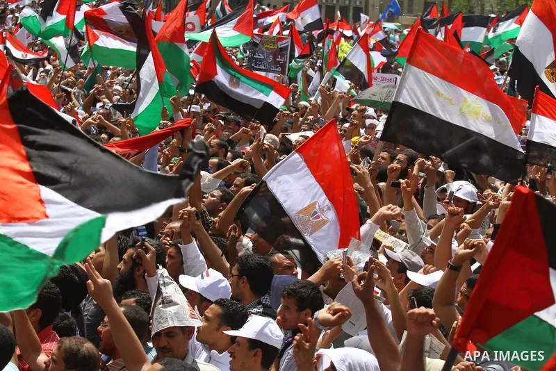 Egyptian demonstrators wave Palestinian flags and Egyptian flags during a rally at Cairo's Tahrir Square on May 13, 2011 during a protest calling for national unity after attacks on Egyptian churches, and solidarity with...