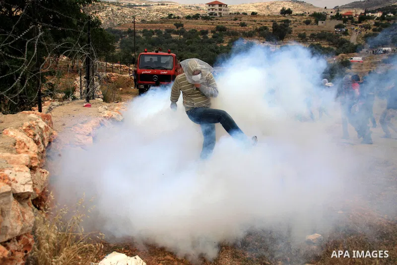 A Palestinian protester kicks back a tear gas canister towards Israeli troops during a protest against Israel's controversial separation barrier and to mark the 63th anniversary of "Nakba" (catastrophe) on May 13, 2011in...