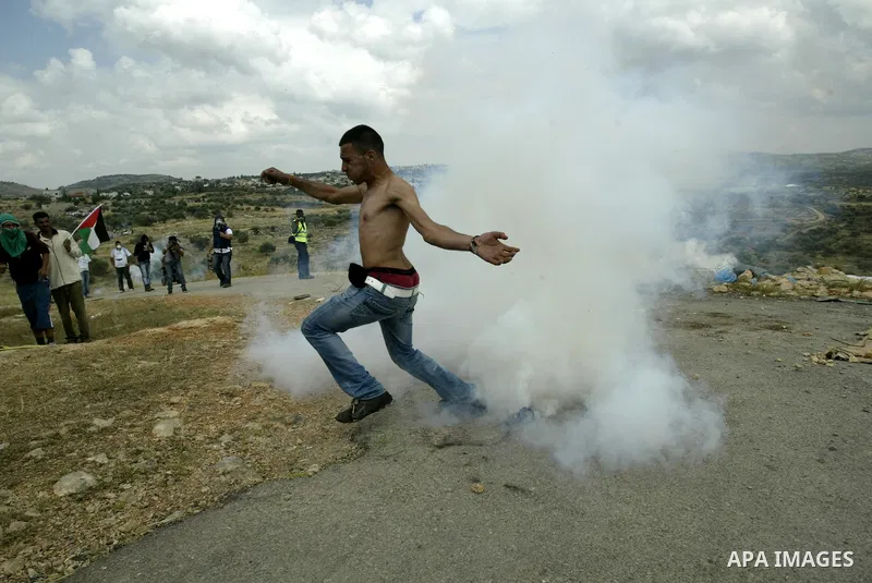A Palestinian protester kicks back a tear gas canister towards Israeli troops during a protest against Israel's controversial separation barrier and to mark the 63th anniversary of "Nakba" (catastrophe) on May 13, 2011in...