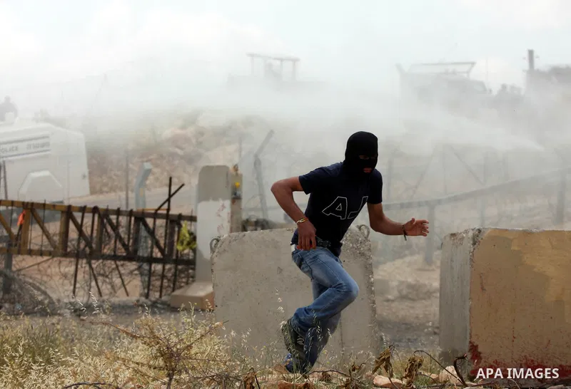 A Palestinian protestor run for cover from tear gas canisters during a protest against Israel's controversial separation barrier and to mark the 63th anniversary of "Nakba" (catastrophe) on May 13, 2011in the West Bank v...