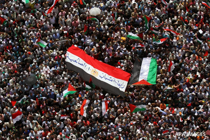 Egyptian demonstrators wave Palestinian flags and Egyptian flags during a rally at Cairo's Tahrir Square on May 13, 2011 during a protest calling for national unity after attacks on Egyptian churches, and solidarity with...