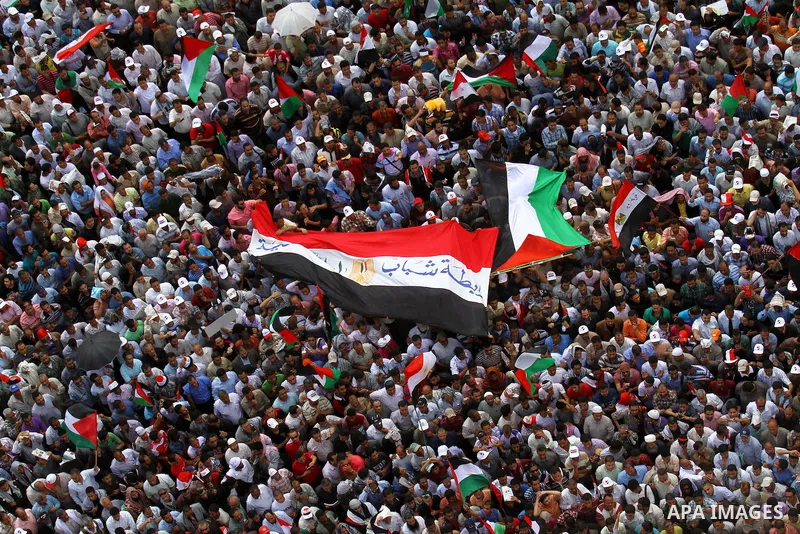 Egyptian demonstrators wave Palestinian flags and Egyptian flags during a rally at Cairo's Tahrir Square on May 13, 2011 during a protest calling for national unity after attacks on Egyptian churches, and solidarity with...