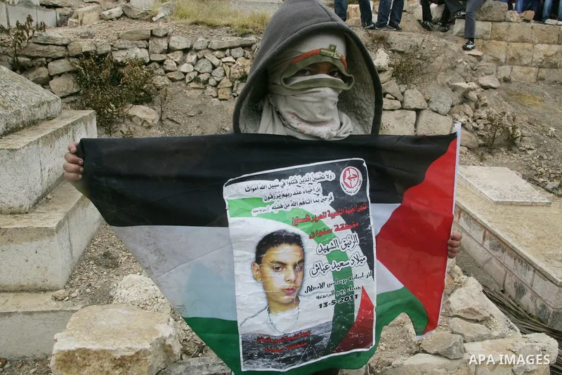Palestinians hold national flag during clashes following the funeral of a teenager who died after being shot as Palestinians launched events to mourn the 1948 creation of the Jewish state in Jerusalem the day before, aft...