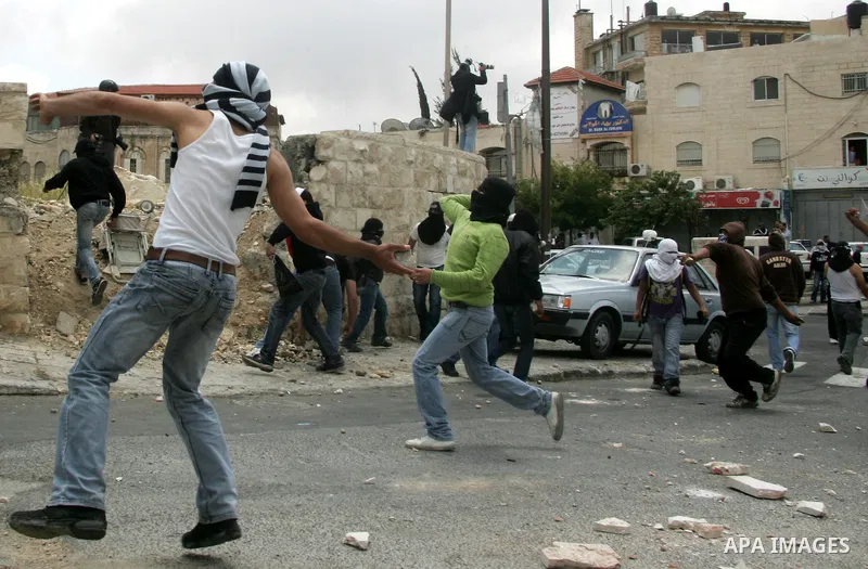 Palestinian youths throw stones during clashes following the funeral of a teenager who died after being shot as Palestinians launched events to mourn the 1948 creation of the Jewish state in Jerusalem the day before, aft...