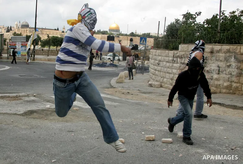 A Palestinian throws a rock during clashes following the funeral of a teenager who died after being shot as Palestinians launched events to mourn the 1948 creation of the Jewish state in Jerusalem the day before, after h...