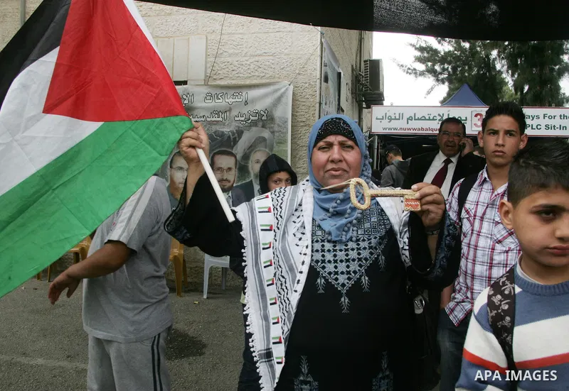Palestinians hold national flag during clashes following the funeral of a teenager who died after being shot as Palestinians launched events to mourn the 1948 creation of the Jewish state in Jerusalem the day before, aft...