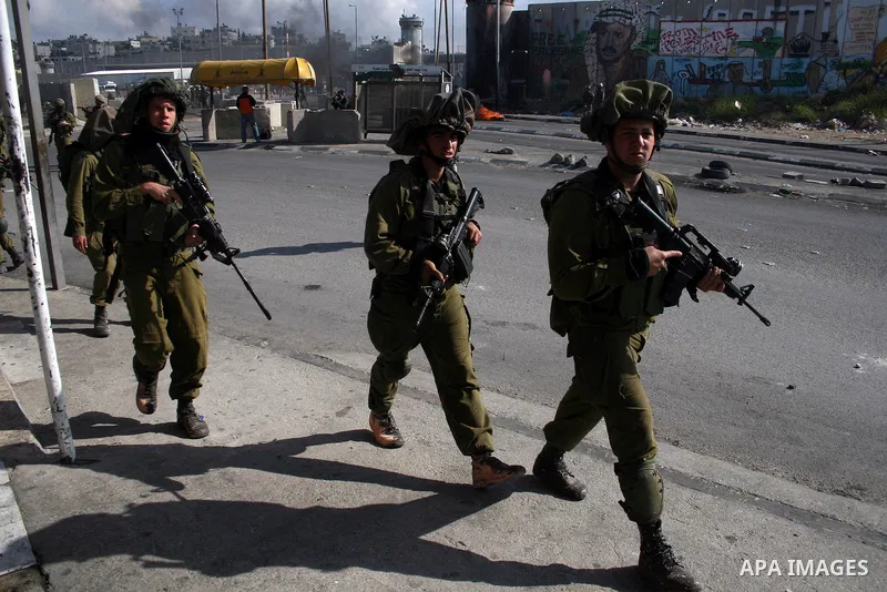 Israeli soldiers run past burning tires during clashes with Palestinian stone throwers at the Israeli manned Qalandia checkpoint between Jerusalem and the West Bank city if Ramallah on May 14, 2011, as Palestinians gathe...