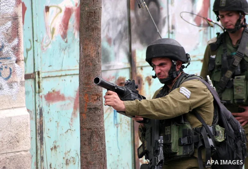 An Israeli soldier fires tear gas canister toward Palestinian youths during confrontations in the restive West Bank city of Hebron as heavy clashes broke out near Ramallah and Jerusalem while Palestinians mourned on May...