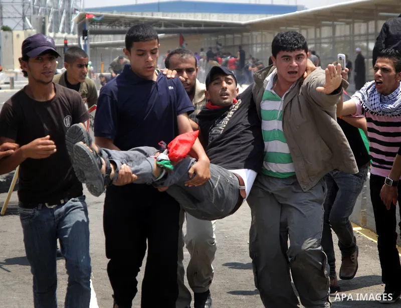 Palestinians carry a wounded protester after Israeli troops opened fire during a massive march heading towards the Erez border crossing in the northern Gaza Strip, on May 15, 2011, as people gathered to mark the "nakbah"...