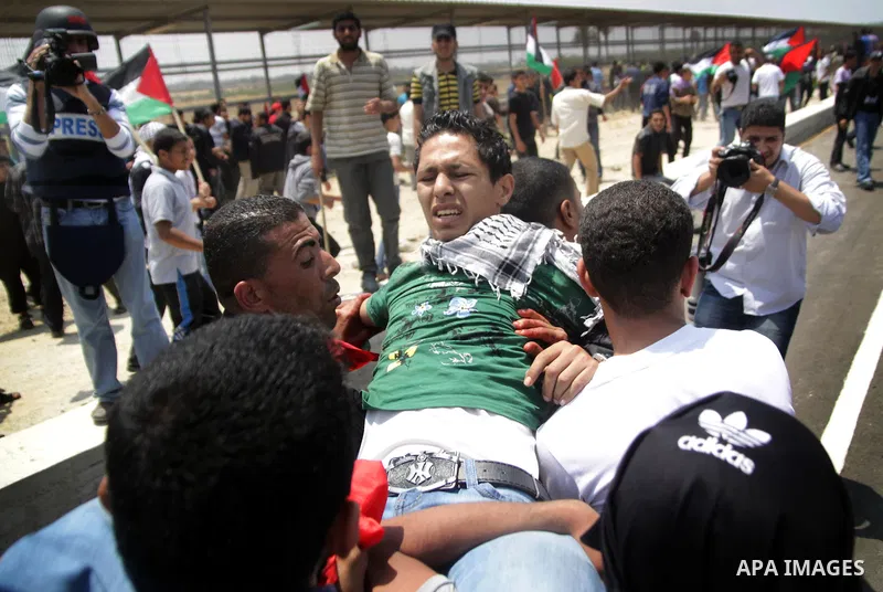 Palestinians carry a wounded protester after Israeli troops opened fire during a massive march heading towards the Erez border crossing in the northern Gaza Strip, on May 15, 2011, as people gathered to mark the "nakbah"...