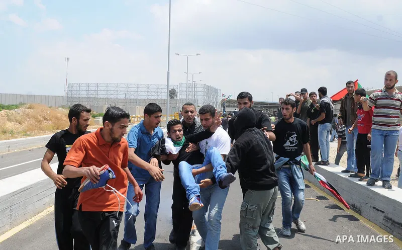 Palestinians carry a wounded protester after Israeli troops opened fire during a massive march heading towards the Erez border crossing in the northern Gaza Strip, on May 15, 2011, as people gathered to mark the "nakbah"...