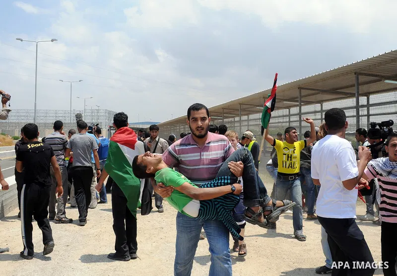 Palestinians carry a wounded protester after Israeli troops opened fire during a massive march heading towards the Erez border crossing in the northern Gaza Strip, on May 15, 2011, as people gathered to mark the "nakbah"...