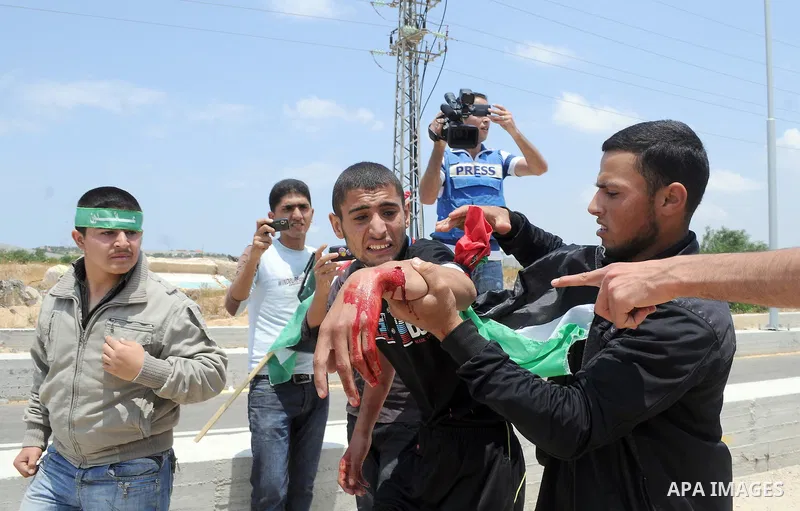 Palestinians carry a wounded protester after Israeli troops opened fire during a massive march heading towards the Erez border crossing in the northern Gaza Strip, on May 15, 2011, as people gathered to mark the "nakbah"...