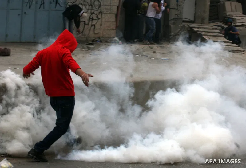 A Palestinian youth throws back a tear gas canister during clashes with Israeli soldiers at the Israeli manned Qalandia checkpoint between Jerusalem and the West Bank city of Ramallah on May 15, 2011. Palestinians across...
