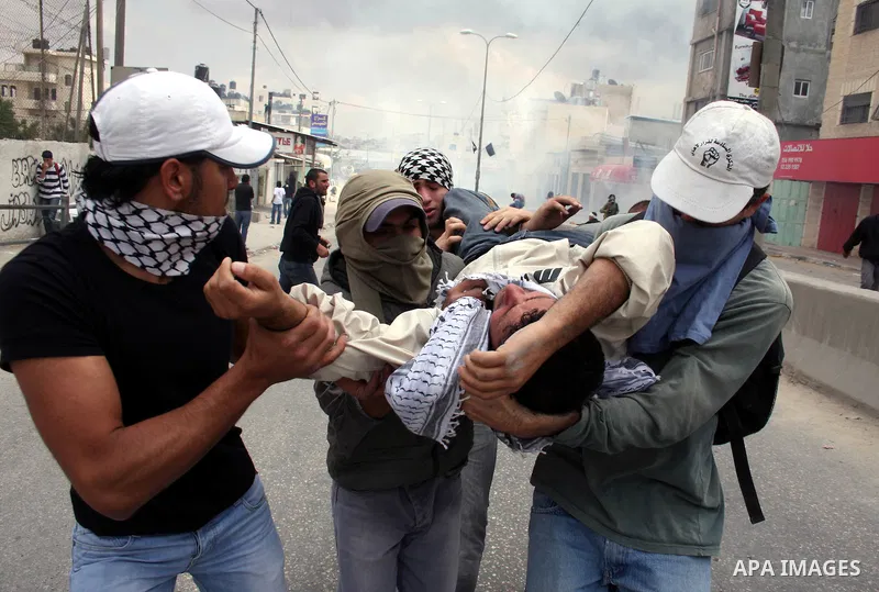 A Palestinian youth is carried away as Israeli soldiers fire tear gas canisters during clashes with Palestinian stone throwers at the Israeli manned Qalandia checkpoint between Jerusalem and the West Bank city of Ramalla...