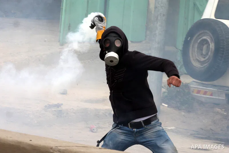 A Palestinian youth throws back a tear gas canister during clashes with Israeli soldiers at the Israeli manned Qalandia checkpoint between Jerusalem and the West Bank city of Ramallah on May 15, 2011. Palestinians across...