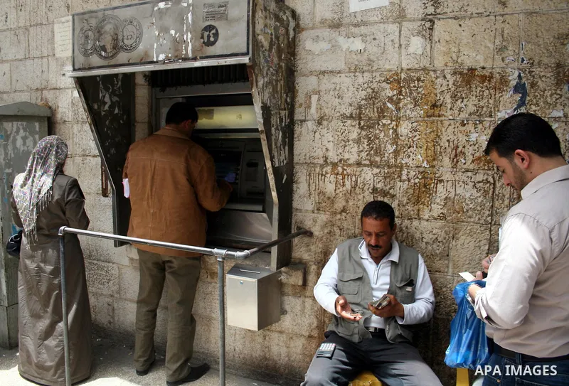 Palestinians receive their salaries for the month of May through ATMs banks in the West Bank city of Ramallah on May 17, 2011, as Palestinian Authority delayed to pay salaries for this month after Israel banned in paymen...