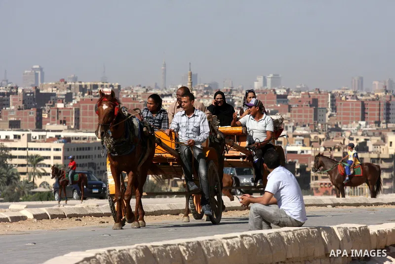 Foreign tourists ride horses and Rockaway near the Giza Pyramids at the outskirts of Cairo, capital of Egypt. in this picture taken May 11, 2011. Photo by Ashraf Amra