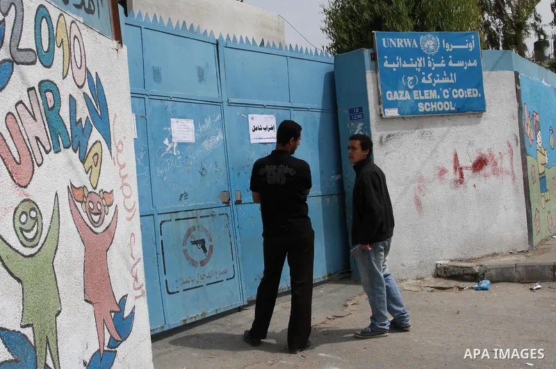 Palestinian men stand in front of United Nations Relief and Works Agency (UNRWA) closed school in Gaza City May 18, 2011 as UN Palestinian employees stage a one day-strike demanding higher wages. Some 16 thousand Palesti...