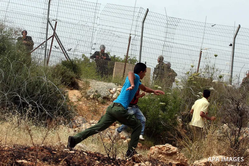 Palestinian demonstrators run for cover from tear gas canisters fired by Israeli soldiers during the weekly demonstration against Israel's separation barrier in the West Bank village of Bilin, near Ramallah, Friday, May...