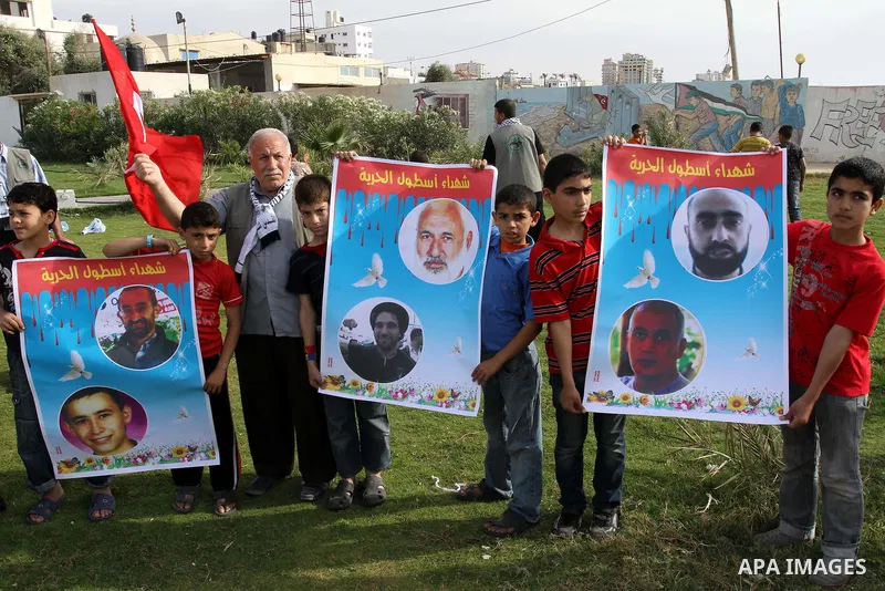 Palestinian children hold, during a protest, pictures of the dead Turkish activists who killed by Israeli navy in the 2nd anniversary of their killing, in Gaza City on May 21,2011. Photo by Mohammed Asad