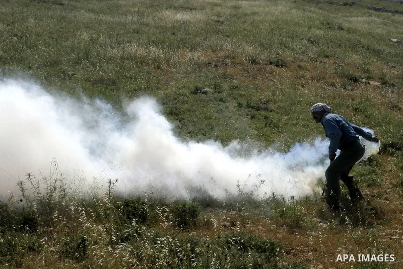 Palestinian and foreign protesters run from tear gas fired by Israeli soldiers, during a demonstration against Jewish settlements in the northern West Bank village of Iraq Burin, near Nablus, Saturday, May 21, 2011. Phot...