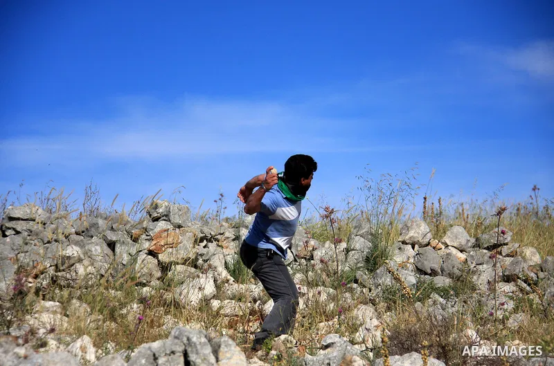 A Palestinian protester hurls stones toward Israeli soldiers, during a demonstration against Jewish settlements in the northern West Bank village of Iraq Burin, near Nablus, Saturday, May 21, 2011. Photo by Wagdi Eshtaya...