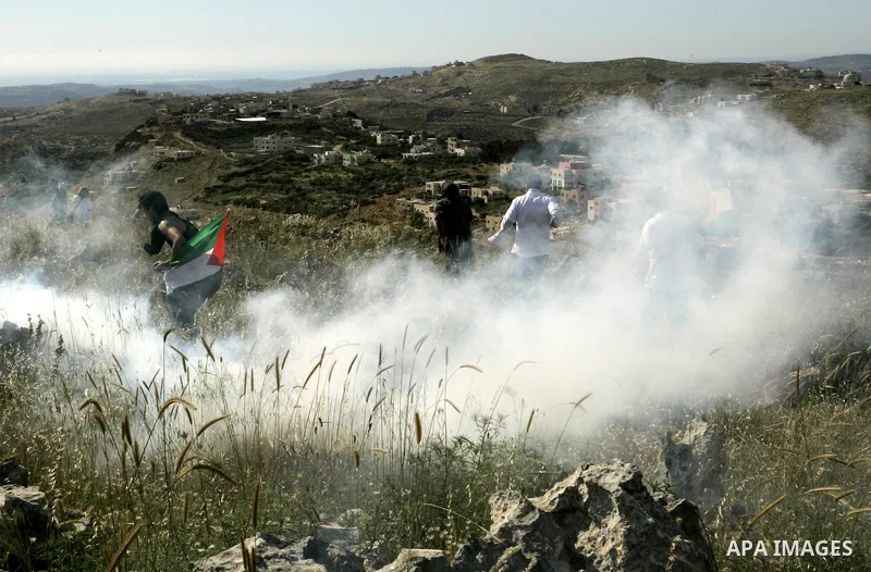 Palestinian and foreign protesters run from tear gas fired by Israeli soldiers, during a demonstration against Jewish settlements in the northern West Bank village of Iraq Burin, near Nablus, Saturday, May 21, 2011. Phot...