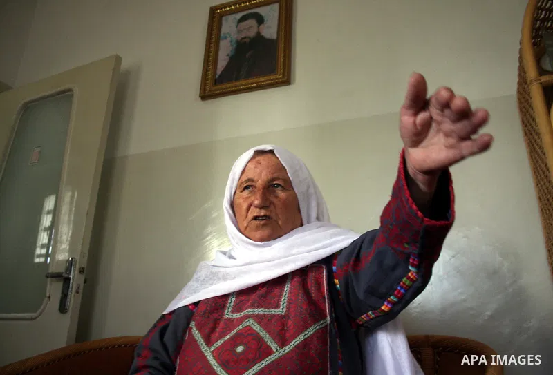 Aisha Aruri, mother of Salah Aruri (portrait top), a senior member of Hamas exiled in Syria, speaks to the press after she was released from a 24-hours Israeli detention in the West Bank city of Ramallah on May 24, 2011....