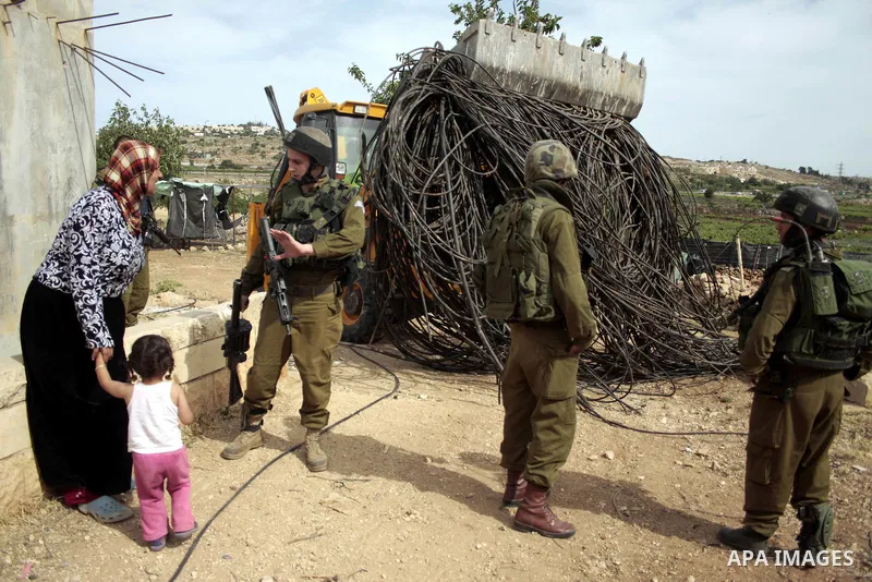 Israeli soldiers stand guard destroy agriculture land partially, and a Palestinian woman argue with the Israeli soldiers near the West Bank City of Hebron across the road from the Israeli settlement of Kiryat Arba on May...