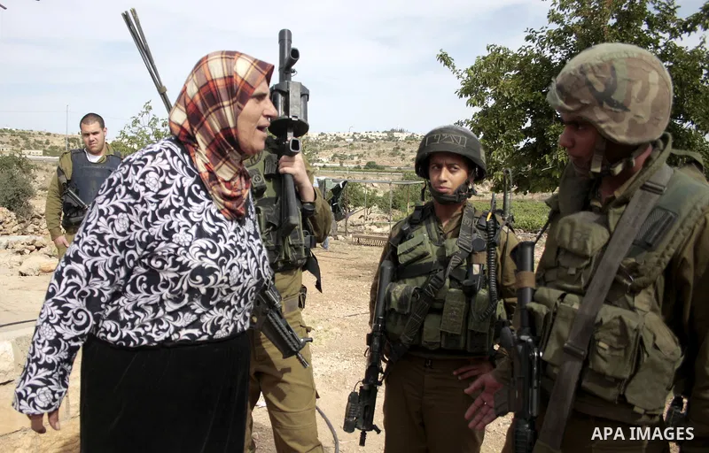 Israeli soldiers stand guard destroy agriculture land partially, and a Palestinian woman argue with the Israeli soldiers near the West Bank City of Hebron across the road from the Israeli settlement of Kiryat Arba on May...
