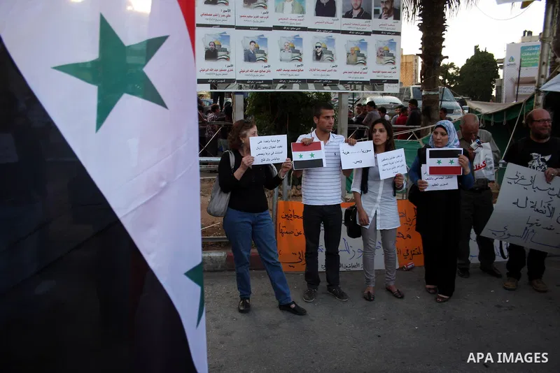 Palestinians hold Syrian flags and signs as they join a demonstration in the West Bank city of Ramallah on May 26, 2011 in support of the Syrian opposition as Syria's pro-democracy movement has reached out to the army ah...