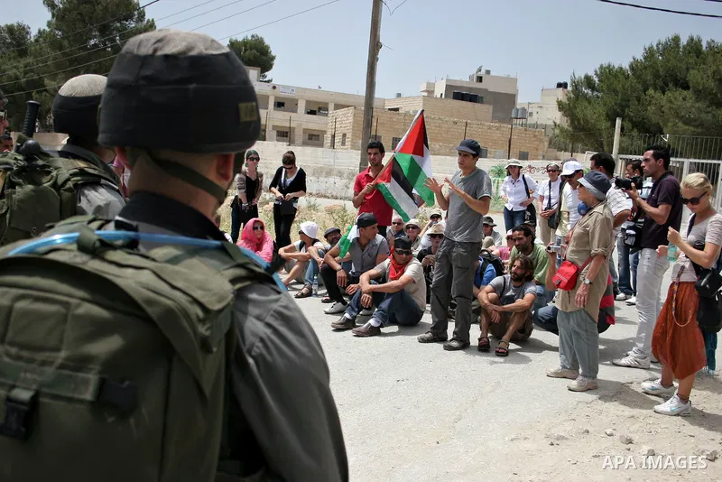 Israeli soldiers stand guard near Palestinians and foreign peace activists taking part in a demonstration against Israel's controversial separation barrier in the West Bank village of Maasarah, near Bethlehem, on May 27,...