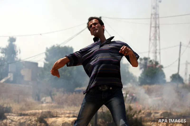 A Palestinian protester hurls stones toward Israeli soldiers during a protest against the expropriation of Palestinian land to expand the Jewish settlement of Halmish, in the West Bank village of Nabi Saleh, on May 27, 2...