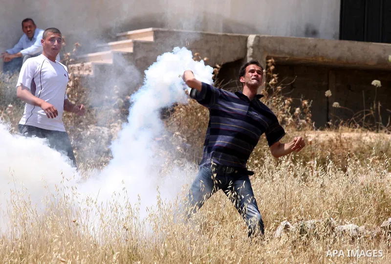 A Palestinian protester hurls back a tear gas canister toward Israeli soldiers during a protest against the expropriation of Palestinian land to expand the Jewish settlement of Halmish, in the West Bank village of Nabi S...