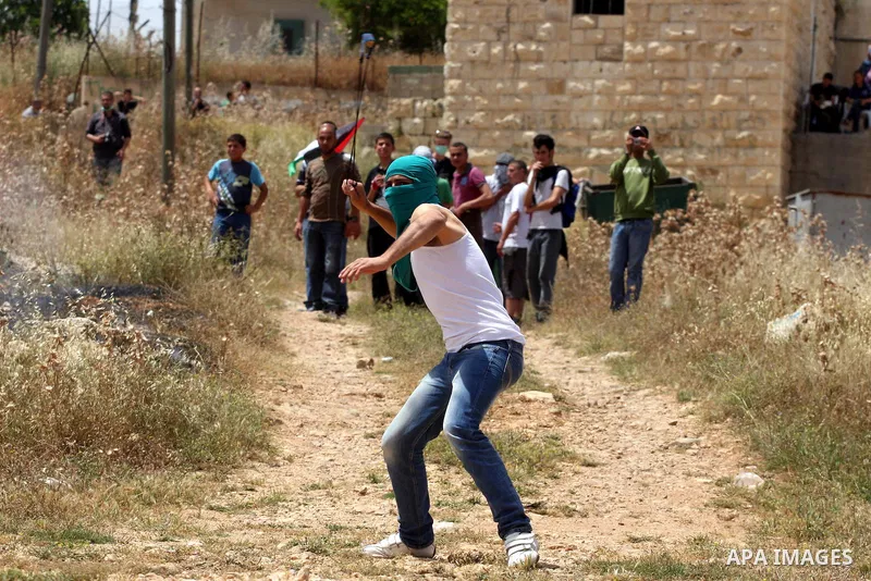 A Palestinian protester uses a sling-shot to hurl stones toward Israeli soldiers during a protest against the expropriation of Palestinian land to expand the Jewish settlement of Halmish, in the West Bank village of Nabi...