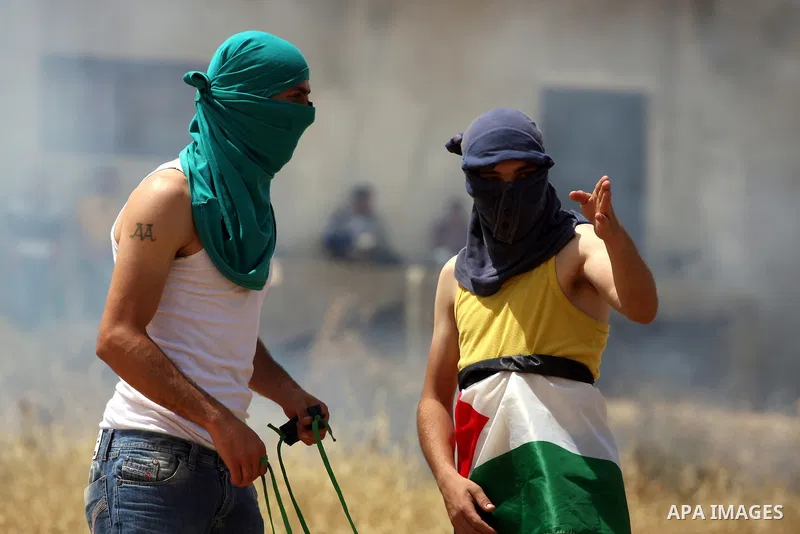 A Palestinian protester uses a sling-shot to hurl stones toward Israeli soldiers during a protest against the expropriation of Palestinian land to expand the Jewish settlement of Halmish, in the West Bank village of Nabi...