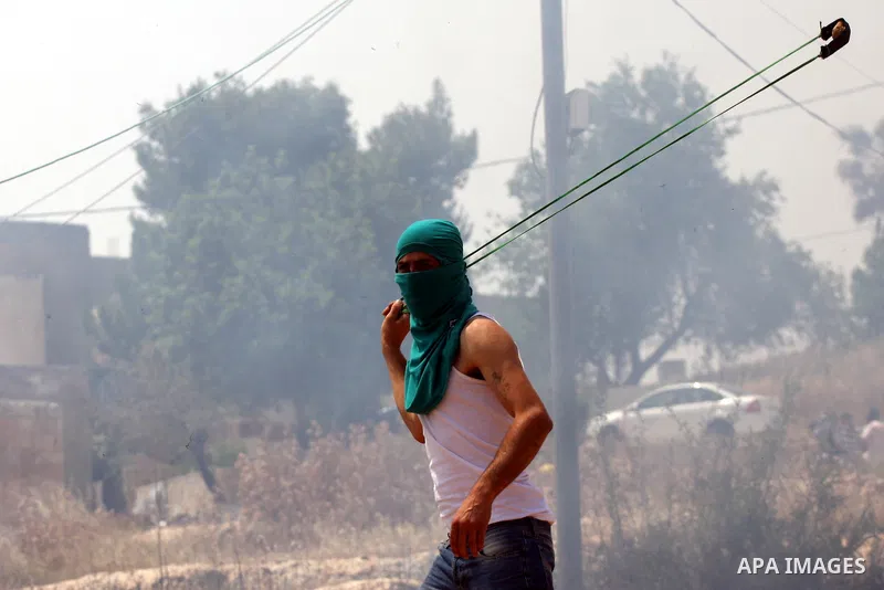 A Palestinian protester uses a sling-shot to hurl stones toward Israeli soldiers during a protest against the expropriation of Palestinian land to expand the Jewish settlement of Halmish, in the West Bank village of Nabi...
