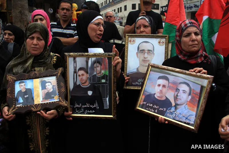 Palestinians hold pictures of their relatives, during a protest calling for the release of Palestinian prisoners from Israeli jails, in the West Bank city of Nablus on May 28, 2011. Israel currently holds about 8,000 Pal...