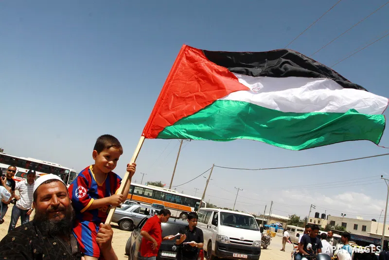 Palestinians wave with their national flag and Egyptian flag at Rafah border crossing in the southern Gaza Strip on May 28, 2011 as Egypt reopened the border, allowing people to cross freely for the first time in four ye...